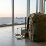 Travel backpack standing beside a cabin bag sizer at a sunlit airport gate